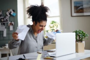 A woman sat at a computer screaming in anger at it trying to figure out the best dispute reason for collections on credit report