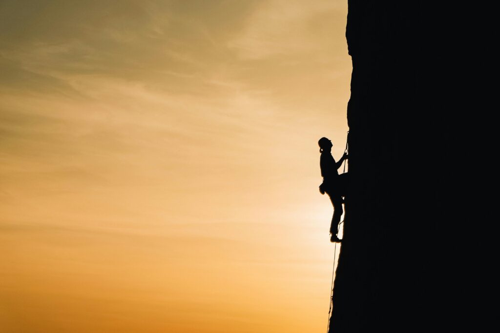 Person rock climbing, a metaphor for them tackling a challenge like climbing out of debt