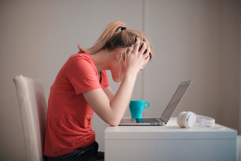 Woman in red t shirt looking at her laptop not happy with her ChexSystem collection request